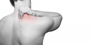 shoulder pain treatment. man holding this shoulder, gripping it as he is in pain